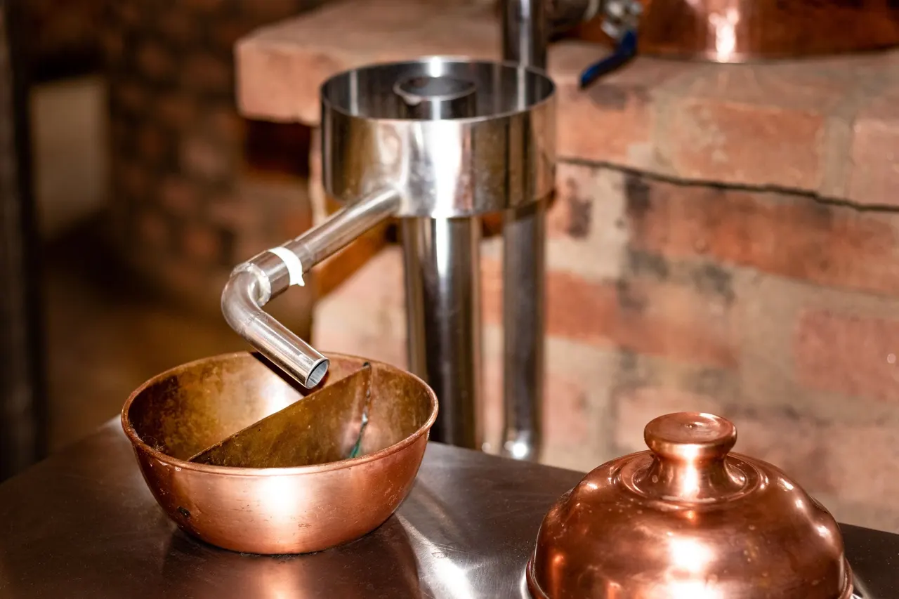 A copper still against an old brick wall
