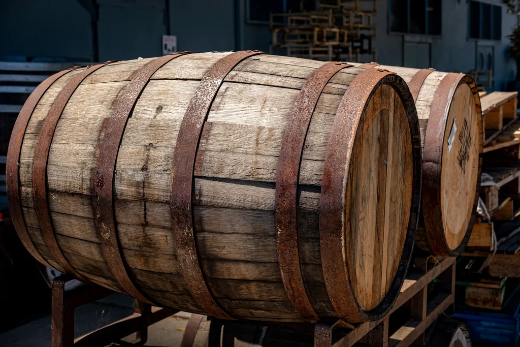 Weathered oak whiskey barrels with rust-colored iron hoops resting on a cart