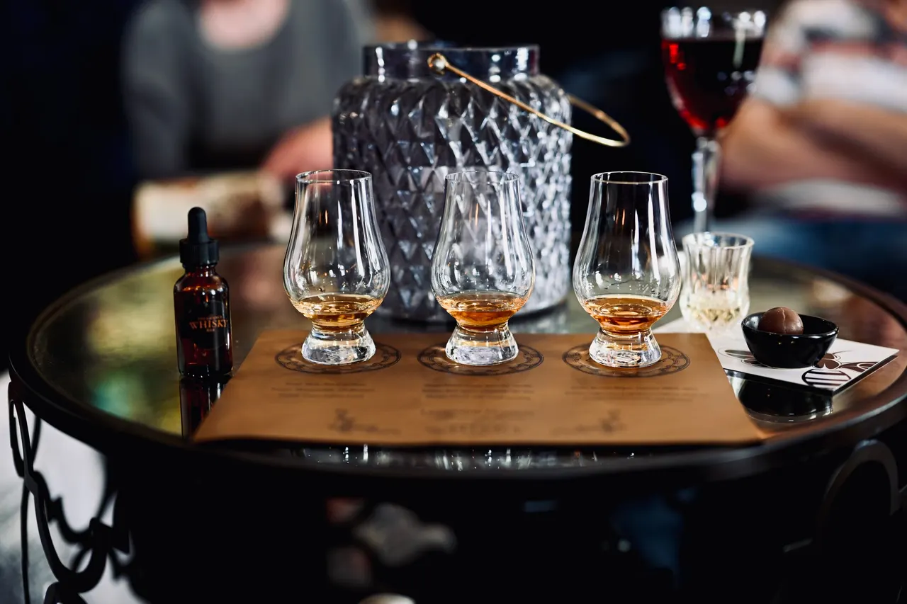 Three tasting glasses of amber whiskey on a round table
