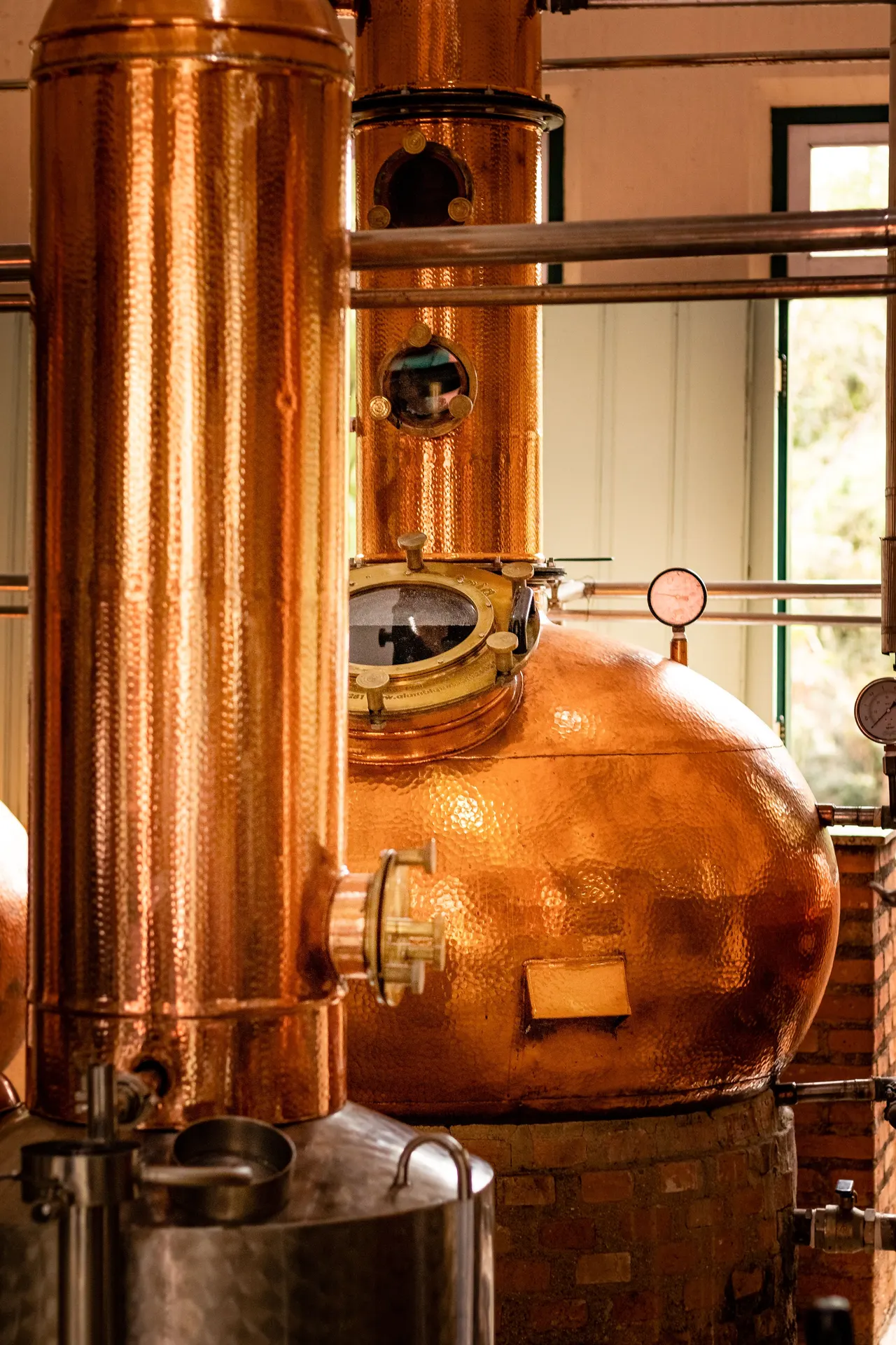 Hammered copper pot still and column inside a distillery